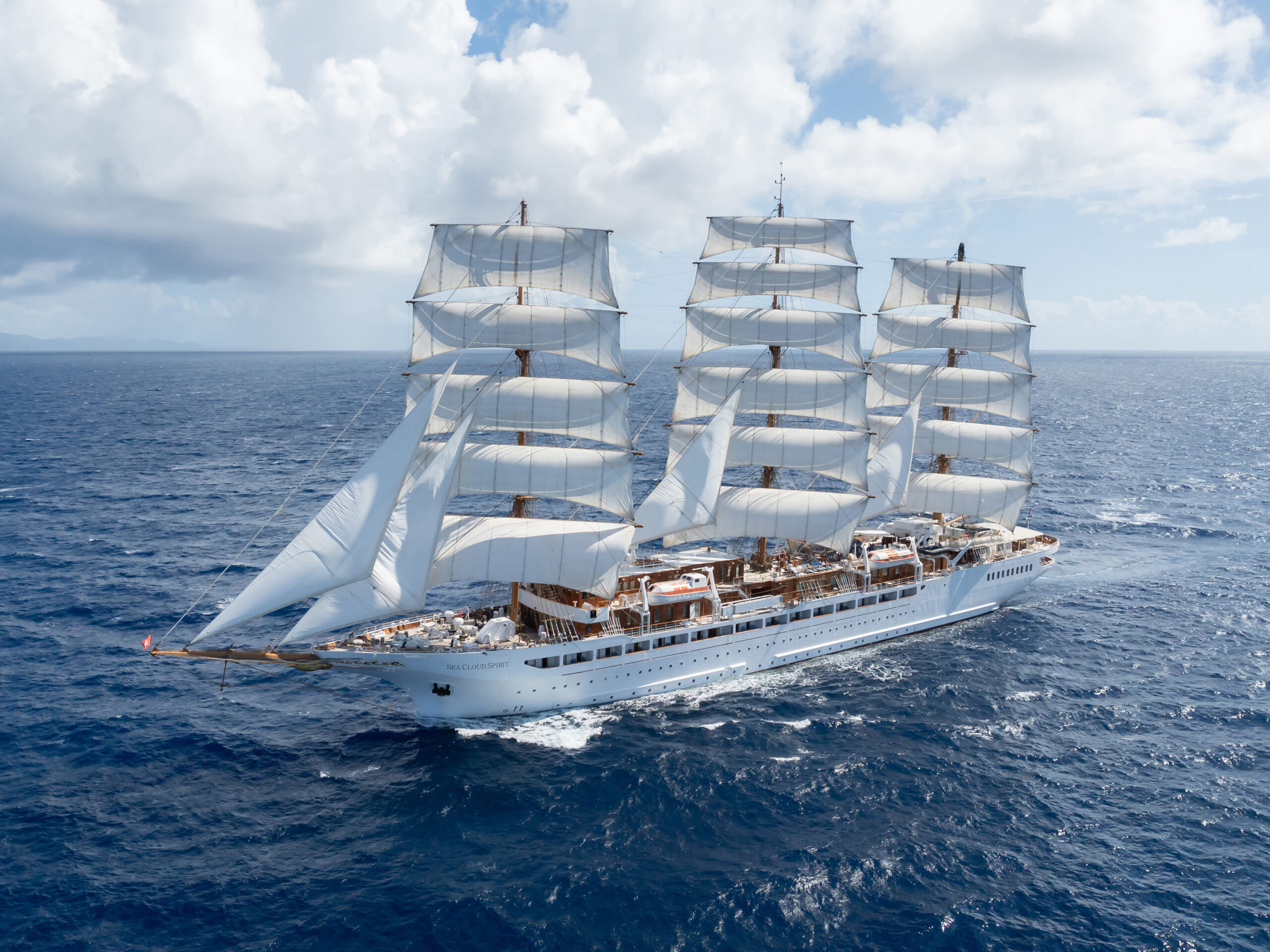 Weißes Dreimast-Segelschiff Sea Cloud Spirit mit vollen Segeln auf offenem Meer unter blauem Himmel