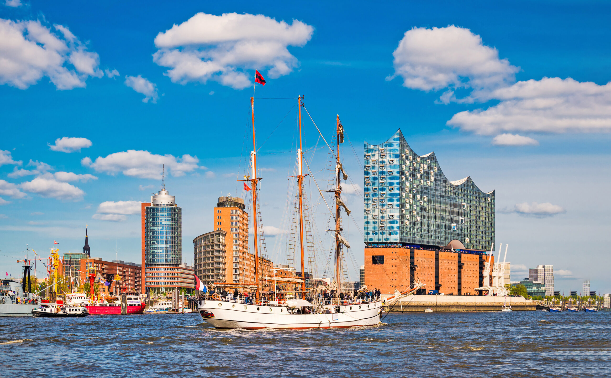 Weißes Segelschiff vor der Elbphilharmonie und moderner Skyline im Hamburger Hafen bei blauem Himmel