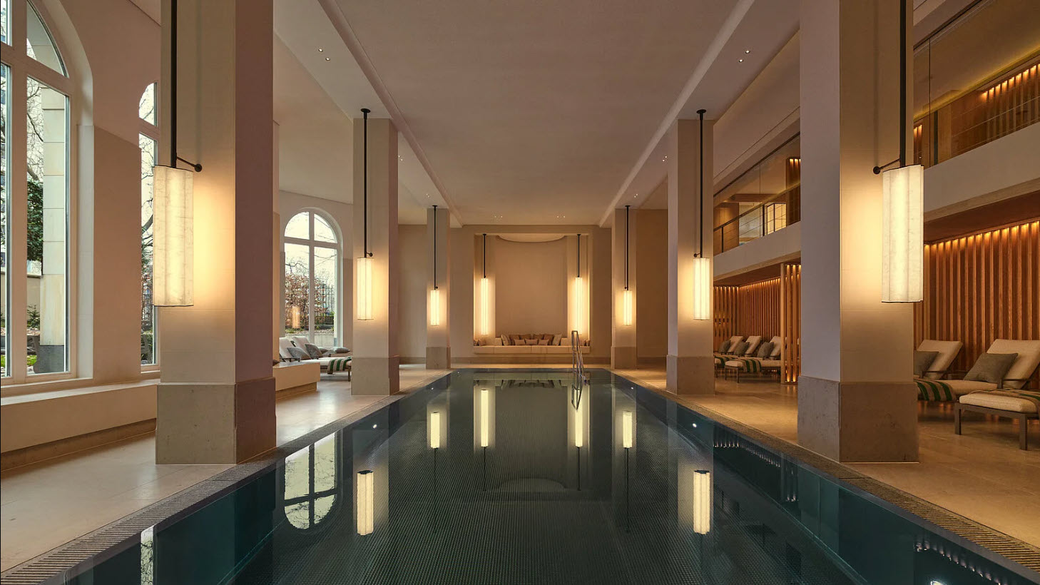 Beleuchteter Innenpool im The Florentin Spa mit großen Fenstern, modernen Säulen und Liegestühlen am Beckenrand